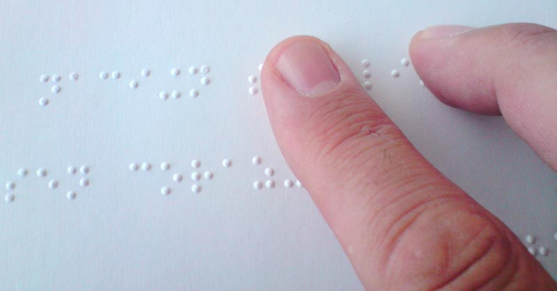 Un doigt lit un texte imprimé en braille