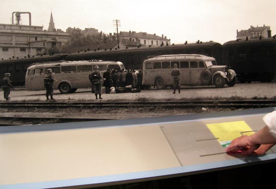 photographie montrant des Juifs raflés par la police. Un visiteur aveugle lit le descriptif correspondant en Braille