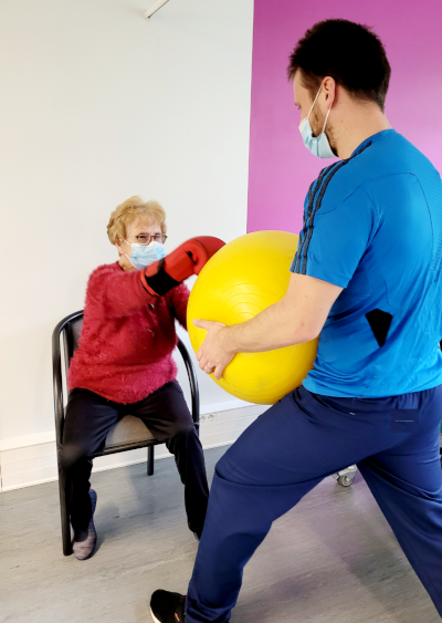 Un enseignant en APA fait marcher une personne âgée dans un ballon